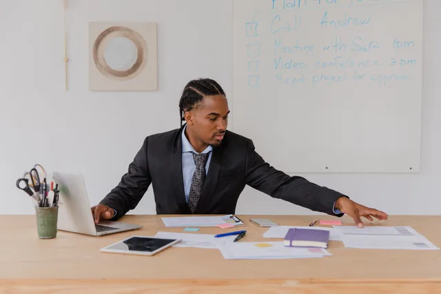 Business professional organizing documents at a desk in a modern office setting. Check the prospecting software team roles you need before you hire
