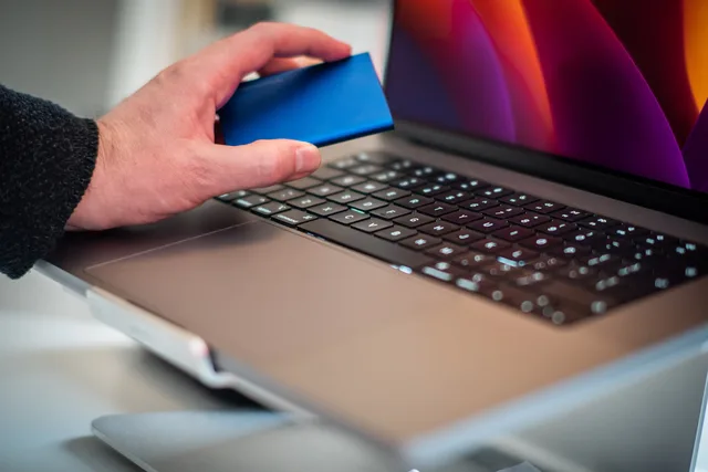 Close-up of a hand holding an external hard drive over a laptop keyboard. When to check lead generation software compliance
