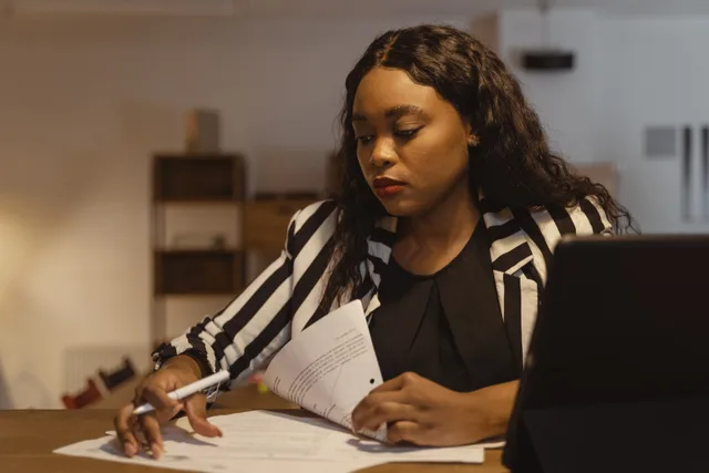 A businesswoman concentrating on paperwork at her office desk, highlighting leadership and focus. Prospecting tools for recruiters: UK shortlist and criteria